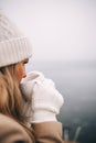 Young pretty woman holding cup of tea enjoying winter frozen nature by the sea Royalty Free Stock Photo