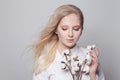 Young pretty woman holding dried cotton flowers on white background
