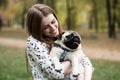 Young pretty woman holding her pet pug dog in the park Royalty Free Stock Photo