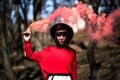 Young pretty woman holding red colorful smoke bomb on the outdoor park. Red smoke spreading in the cerebration festival Royalty Free Stock Photo