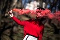 Young pretty woman holding red colorful smoke bomb on the outdoor park. Red smoke spreading in the cerebration festival Royalty Free Stock Photo