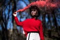 Young pretty woman holding red colorful smoke bomb on the outdoor park. Red smoke spreading in the cerebration festival Royalty Free Stock Photo