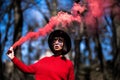 Young pretty woman holding red colorful smoke bomb on the outdoor park. Red smoke spreading in the cerebration festival Royalty Free Stock Photo