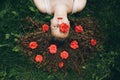 Young woman laying on green grass with red roses in hair. Royalty Free Stock Photo