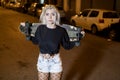 Young pretty woman looking camera in shorts while standing on the street holding a skateboard at night in the city Royalty Free Stock Photo