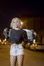 Young pretty woman looking camera in shorts while standing on the street holding a skateboard at night in the city Royalty Free Stock Photo