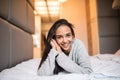 Young pretty woman looking at camera and smiling while lying on the bed at home Royalty Free Stock Photo