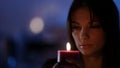 young pretty woman is making a wish holding burning candle, portrait in darkness Royalty Free Stock Photo