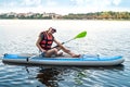 Young pretty woman in orange life vests surfs on supboard in city lake Royalty Free Stock Photo