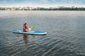 Young pretty woman in orange life vests surfs on supboard in city lake Royalty Free Stock Photo