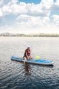 Young pretty woman in orange life vests surfs on supboard in city lake Royalty Free Stock Photo