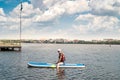 Young pretty woman in orange life vests surfs on supboard in city lake Royalty Free Stock Photo