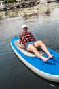 Young pretty woman in orange life vests surfs on supboard in city lake Royalty Free Stock Photo