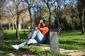 Young, pretty woman in orange t-shirt and jeans, looking at camera, relaxed and calm, sitting on a metal bench in a park. Fashion Royalty Free Stock Photo