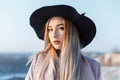 Young pretty woman with pale skin with beautiful make-up with brown eyes, with blond hair in an elegant hat in a pink coat Royalty Free Stock Photo