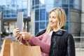 Young pretty woman with paper bags after shopping, holding a tablet in her hands and walking around the city Royalty Free Stock Photo