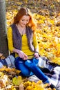 Young pretty woman in the park listening music in autumn