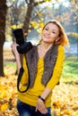 Pretty woman in the park with photocamera in the autumn day