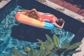 Young pretty woman with perfect tanned body lying on air mattress in the pool in summer and having fun. Relaxing Royalty Free Stock Photo