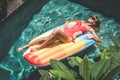 Young pretty woman with perfect tanned body lying on air mattress in the pool in summer and having fun. Relaxing Royalty Free Stock Photo