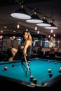 young pretty woman playing alone snooker holding cue at pool table Royalty Free Stock Photo