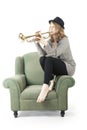 Young pretty woman playing the trumpet sitting on armchair
