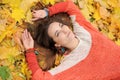 Young pretty woman portrait, laying in autumn leaves, dressed in fashion orange sweater