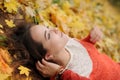 Young pretty woman portrait, laying in autumn leaves and looking on the sky