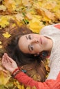 Young pretty woman portrait, laying in autumn leaves