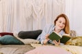 Young pretty woman is reading a book at home in bed. House reading concept, bright interior Royalty Free Stock Photo