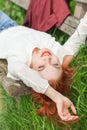 Young pretty woman with red hair lying on garden bench relaxing Royalty Free Stock Photo
