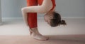 Young pretty woman in red sports tracksuit does leaning forwards in slow motion, person does physical training, yoga