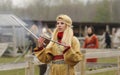 Young pretty woman reenactor dressed like an ancient slavonic girl dancing with sticks, pagan dance. Kyiv Rus park