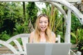 Young pretty woman resting on swing and using laptop, palms in background. Royalty Free Stock Photo