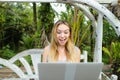 Young pretty woman resting on swing and using laptop, palms in background. Royalty Free Stock Photo