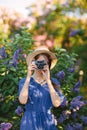 Pretty girl take a photo in lilac blooming garden