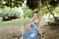 Young pretty woman riding swing and using smatrphone, sand and tree in background. Royalty Free Stock Photo