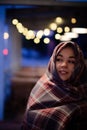 Young pretty woman with a scarf on her head on a cozy terrace on Christmas evening. Cozy autumn evening.