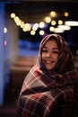 Young pretty woman with a scarf on her head on a cozy terrace on Christmas evening. Cozy autumn evening.