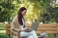 Young pretty woman sitting on bench at the park during summer day and using laptop. Royalty Free Stock Photo