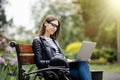 Young pretty woman sitting on bench in the park, using laptop computer, networking online on wireless. Student work on laptop in p Royalty Free Stock Photo