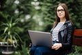 Young pretty woman sitting on bench in the park, using laptop computer, networking online on wireless. Student work on laptop in p Royalty Free Stock Photo