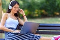 Young pretty woman sitting on bench in the park, using laptop computer Royalty Free Stock Photo