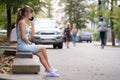 Young pretty woman sitting on a bench talking on her mobile phone outdoors on city street Royalty Free Stock Photo