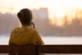 Young pretty woman sitting on a bench talking on her mobile phone outdoors in the evening Royalty Free Stock Photo