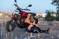 Young pretty  woman sitting on ground next to nake racer motorbike Royalty Free Stock Photo