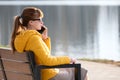 Young pretty woman sitting on a park bench talking on her smartphone outdoors in warm autumn evening Royalty Free Stock Photo