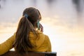 Young pretty woman sitting on a park bench talking on her smartphone outdoors in warm autumn evening Royalty Free Stock Photo