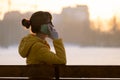 Young pretty woman sitting on a park bench talking on her smartphone outdoors in warm autumn evening Royalty Free Stock Photo