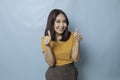 Young pretty woman smiling joyfully and looking happy, feeling carefree and positive with both thumbs up  by blue Royalty Free Stock Photo